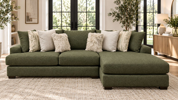 An olive green sectional sofa with a right-facing chaise lounge, styled with multiple textured throw pillows in a bright, modern living room.