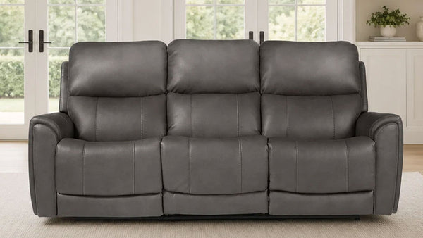 A three-seat gray leather reclining sofa with padded backrests and armrests, shown in a bright living room setting.