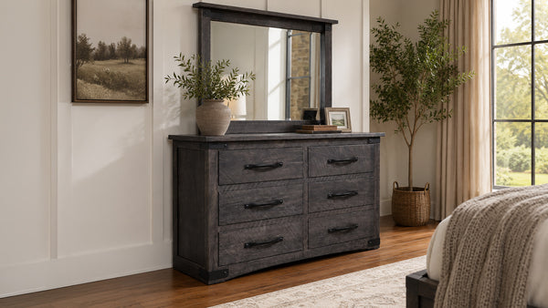 Dark wood dresser with mirror in a bedroom setting with plants and decor.
