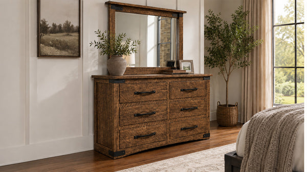 Wooden dresser with mirror in a bedroom setting with plants and decor.