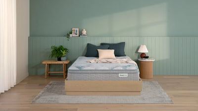 Bedroom with a mattress on a wooden bed frame against a green wall.