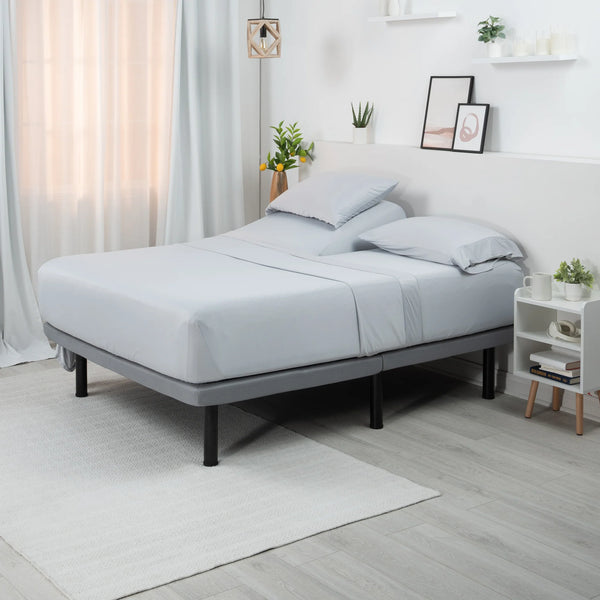 Somier ajustable gris con ropa de cama en un dormitorio