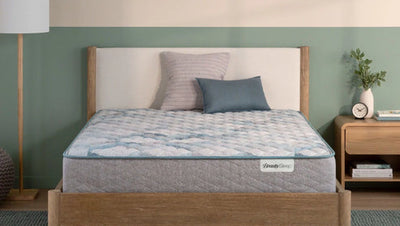 Bed with a mattress on a wooden bed frame against a green wall.