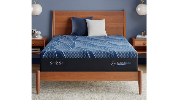 Cama con sobrecolchón azul y cabecero de madera contra una pared azul.