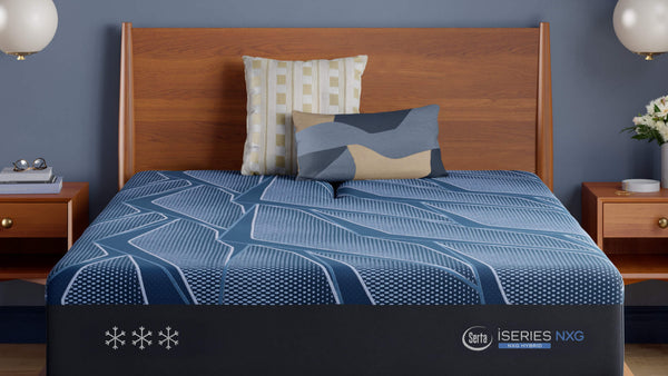 Colchón azul con logotipo de la marca sobre una cama de madera en un dormitorio