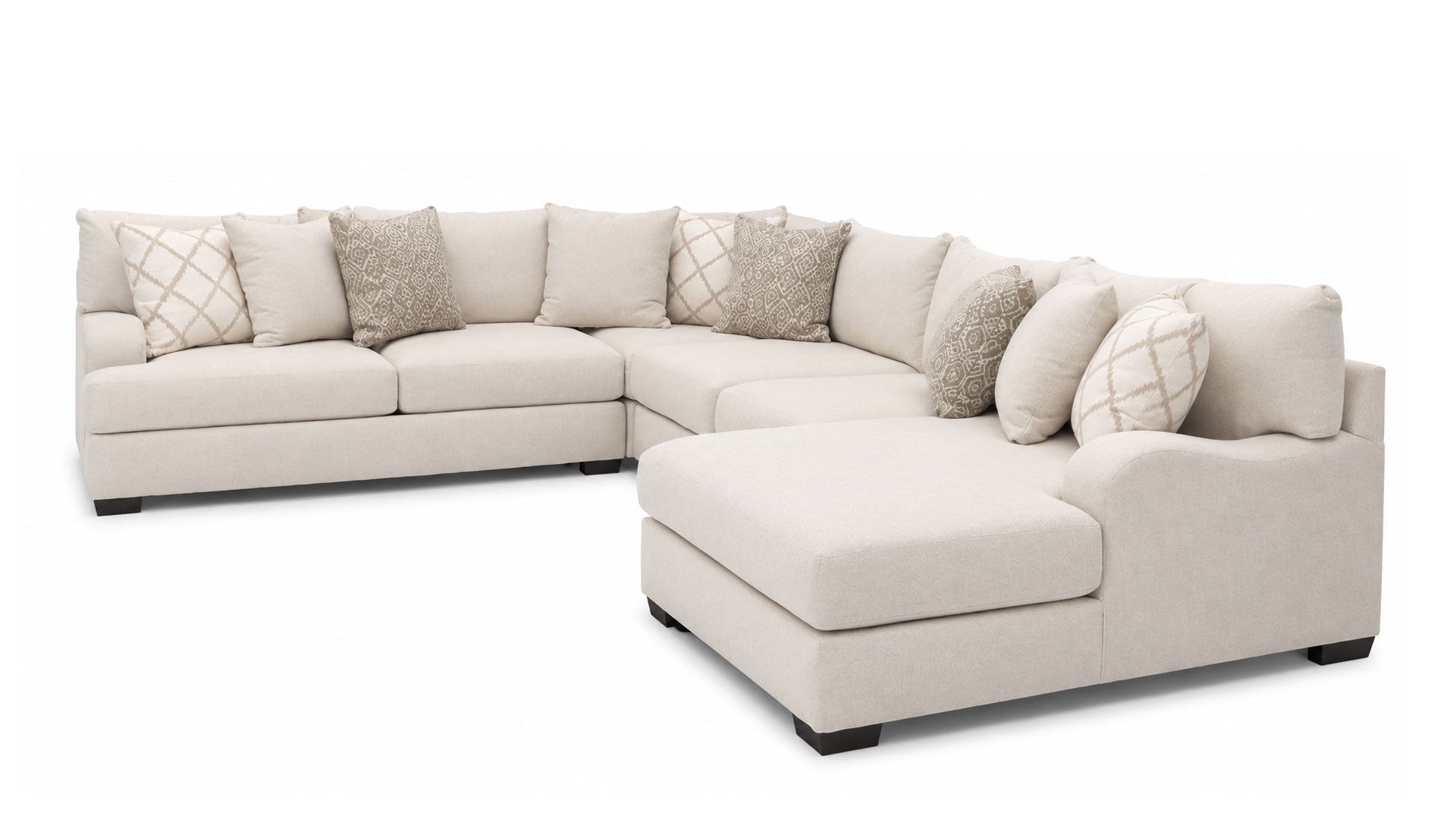 A light beige fabric sectional sofa with a right-facing chaise lounge, styled with multiple decorative throw pillows in neutral tones, shown against a solid white background.