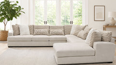 Beige sectional sofa in a living room with large windows and a plant.