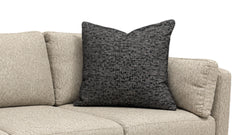 A square dark charcoal gray textured throw pillow resting on a light beige fabric sofa against a plain white background.