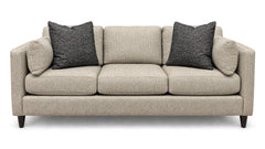 A three-seat upholstered sofa in a light beige textured fabric, featuring two dark gray textured throw pillows and dark wooden legs, shown against a plain white background.