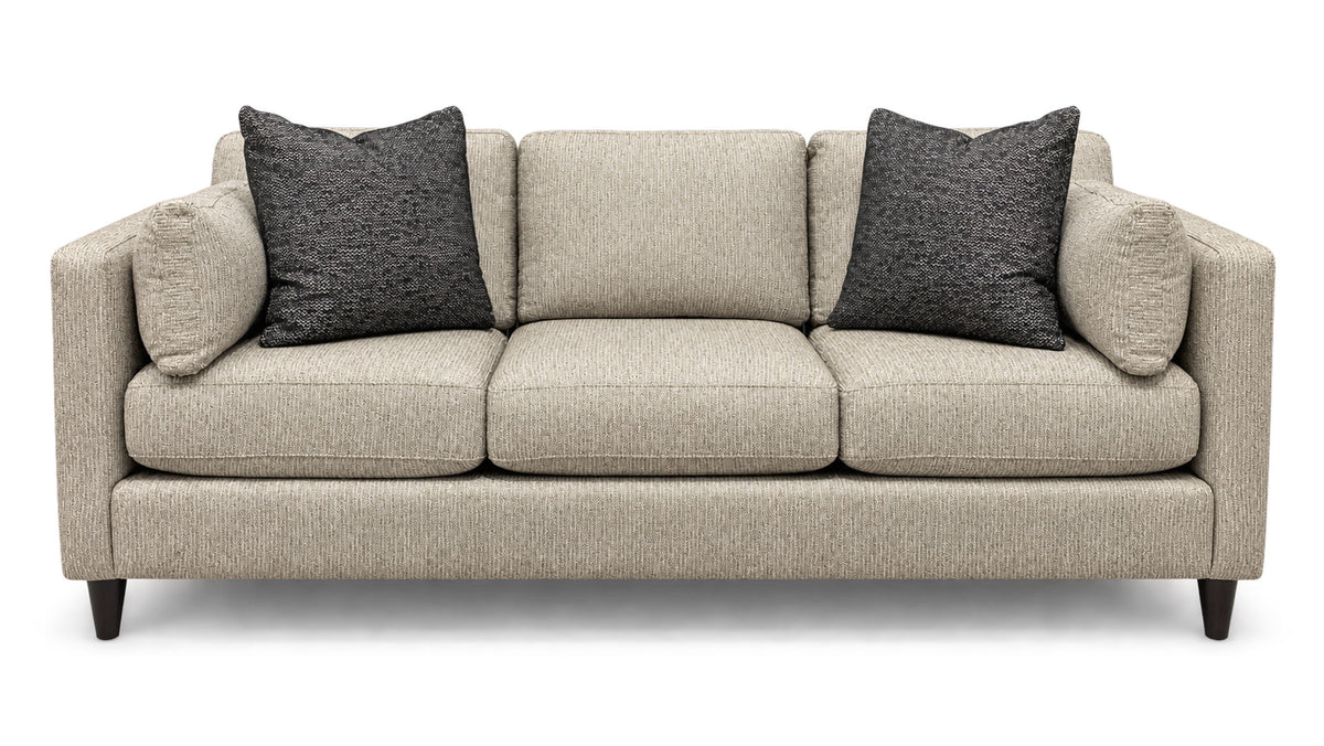 A three-seat upholstered sofa in a light beige textured fabric, featuring two dark gray textured throw pillows and dark wooden legs, shown against a plain white background.