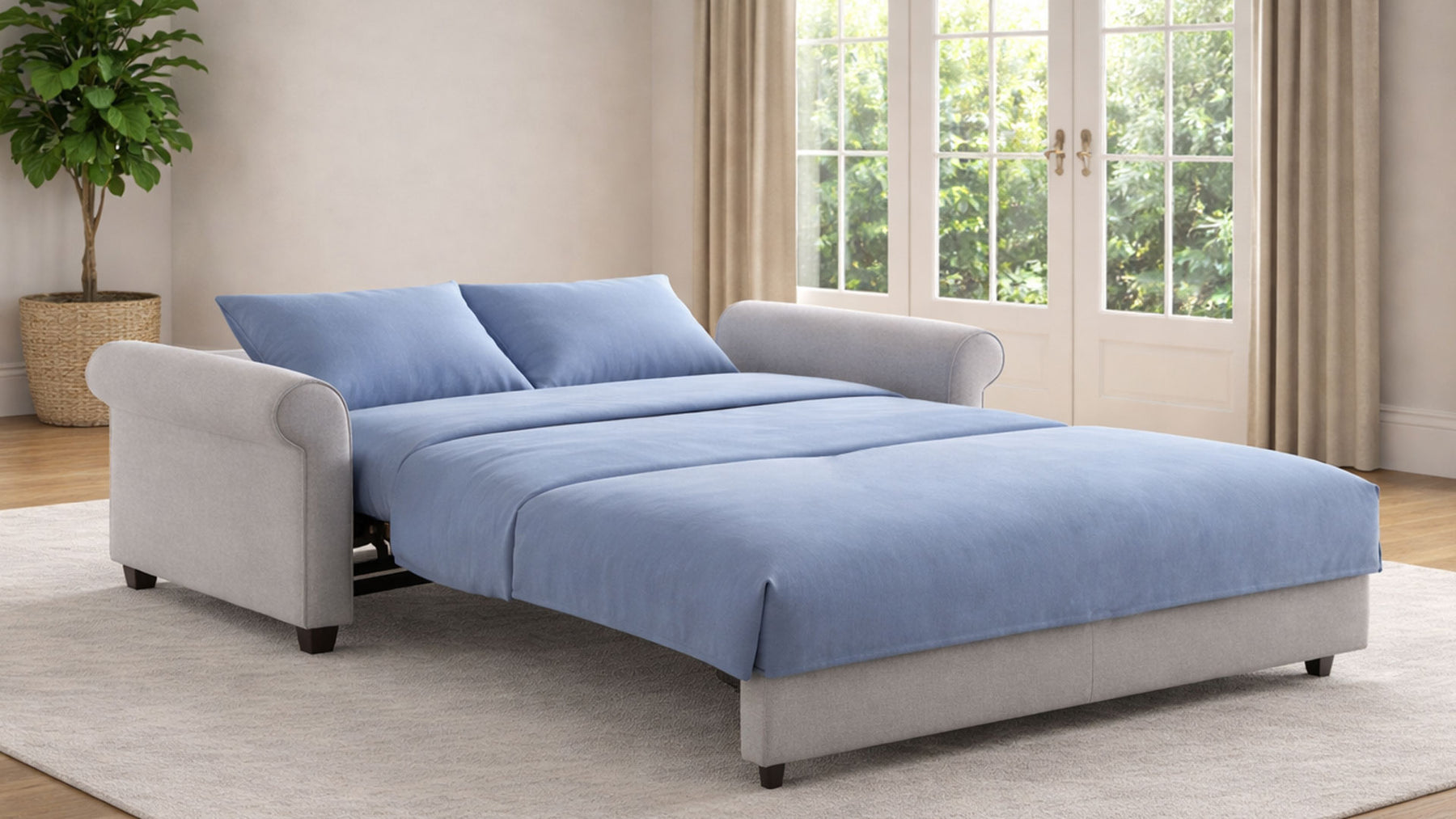 Sofa bed with blue cover in a room with large windows and a plant.
