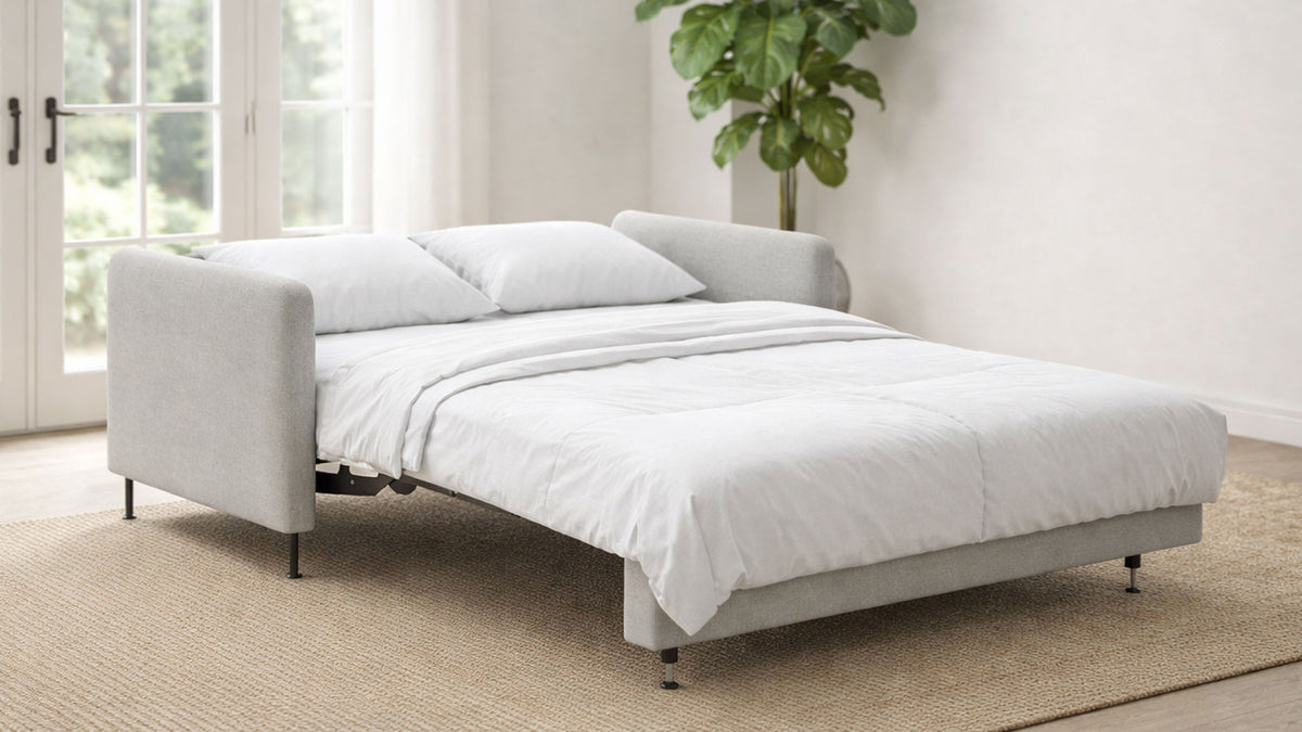 White sofa bed in a room with a plant and window