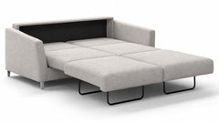 Un sofá-cama futón tapizado en gris claro, con el respaldo negro y patas de metal negras, que se muestra parcialmente desplegado sobre un fondo blanco.