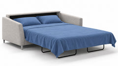 Un sofá cama tapizado en gris claro con una configuración de sofá cama extraíble, que se muestra con ropa de cama azul y dos cojines azules sobre un fondo blanco impecable.