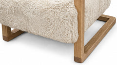 Close-up of a modern armchair or ottoman with a thick, shaggy cream faux-fur upholstery and a light natural wood frame, shown on a white background.
