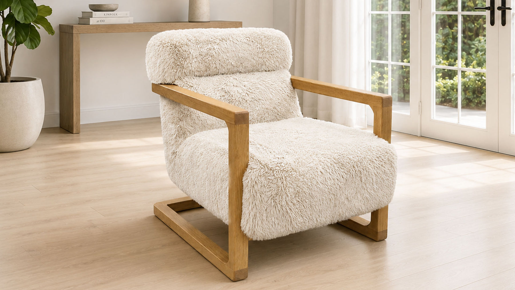 A modern armchair with a fluffy cream bouclé seat and back cushion, supported by a light natural wood frame, shown in a bright, minimalist room with light wood floors and large windows.