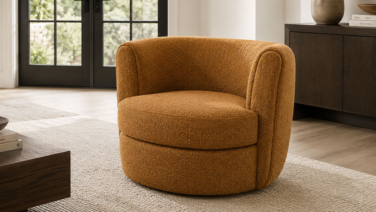 A round barrel-style accent chair upholstered in a textured mustard-yellow bouclé fabric, set in a modern living room with light wood floors, a beige rug, and dark wood furniture.