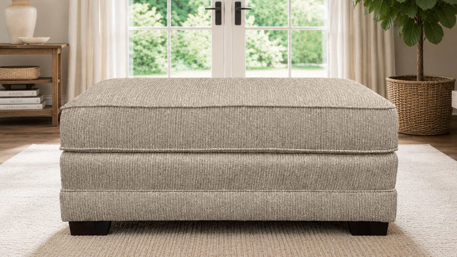 Gray upholstered ottoman in a room with a window and plant