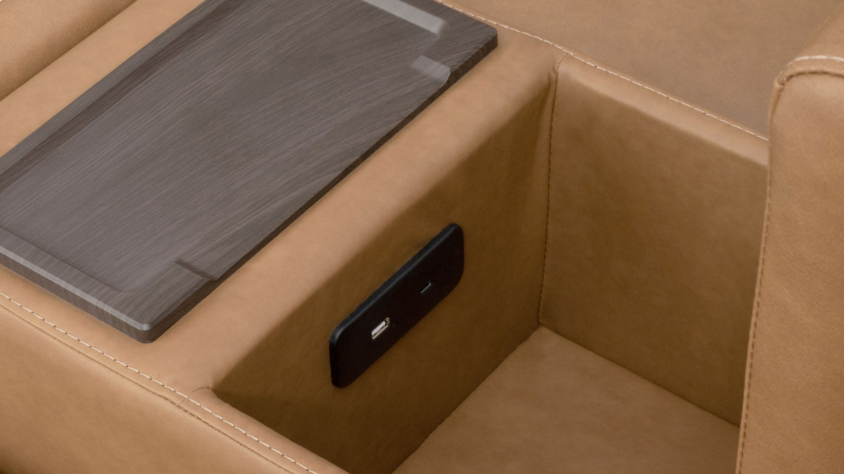 Close-up of a tan leather armchair with a dark wood-look tray table and a built-in black USB charging port.