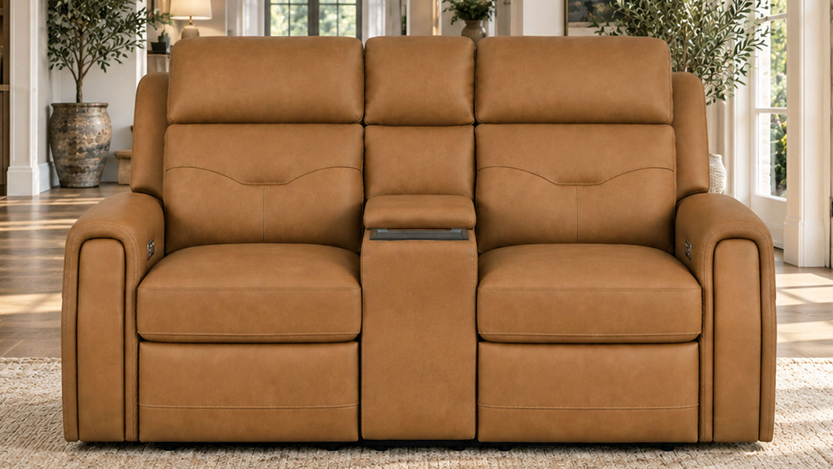 A three-seat reclining loveseat in tan leather, featuring two individual reclining seats, wide armrests, and a central armrest with a built-in media console tray, shown in a bright living room setting.