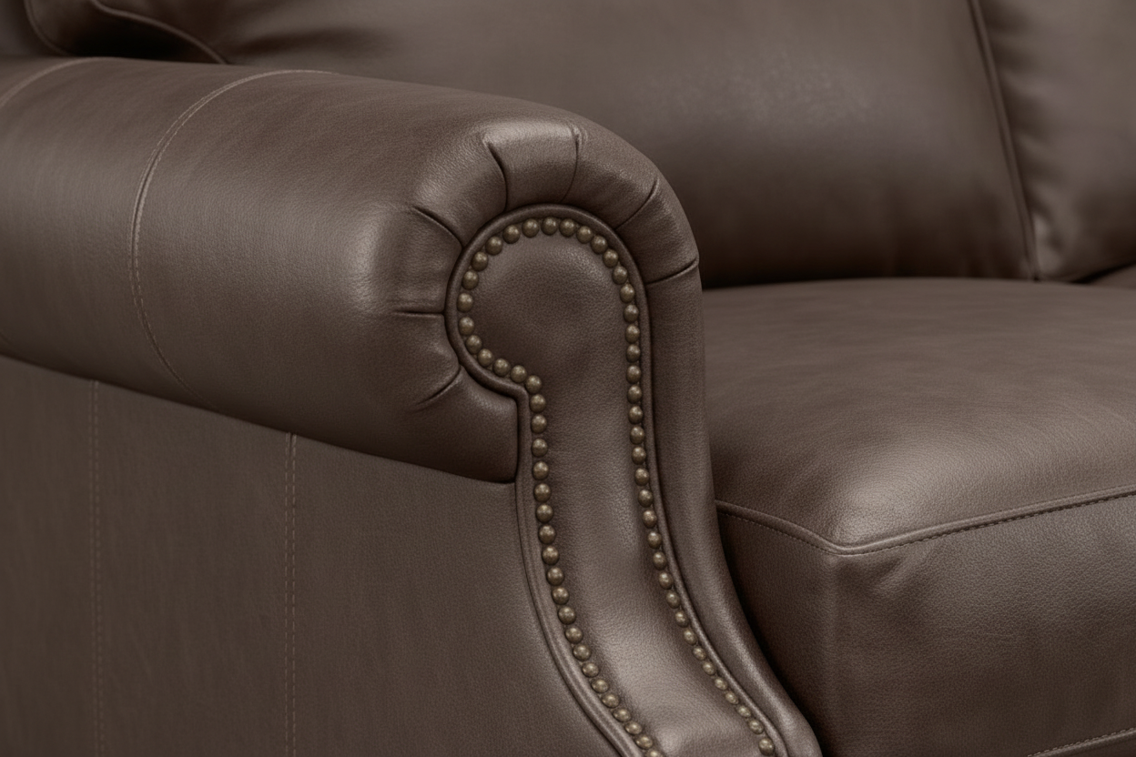 Primer plano de un sillón de cuero marrón con ribete decorativo de tachuelas.