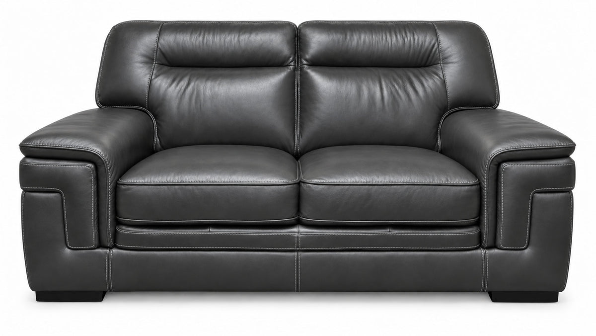 A black leather loveseat sofa with two seat cushions, two back cushions, wide armrests, and a low block base, shown against a plain white background.