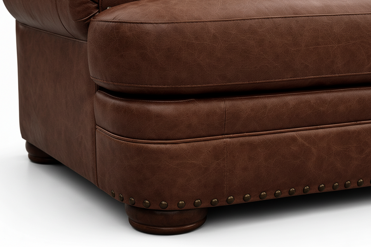 Close-up of a brown leather sofa with visible stitching on a white background