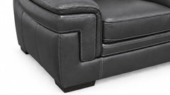 Close-up of a dark gray leather armchair showing the side bolster, channel tufting, and clean stitching on a white background.