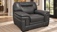 A dark gray leather recliner armchair with a high back and wide armrests, positioned on a textured beige rug in a modern living room setting.