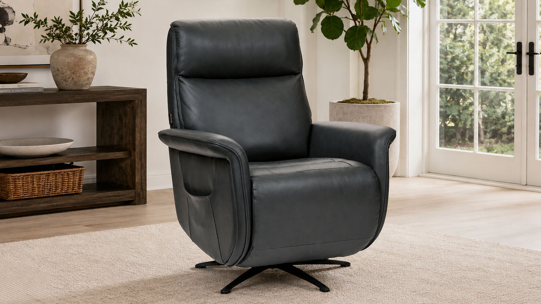 A black leather swivel recliner chair with a side pocket, shown in a bright, modern living room setting with a wooden console table and potted plants.