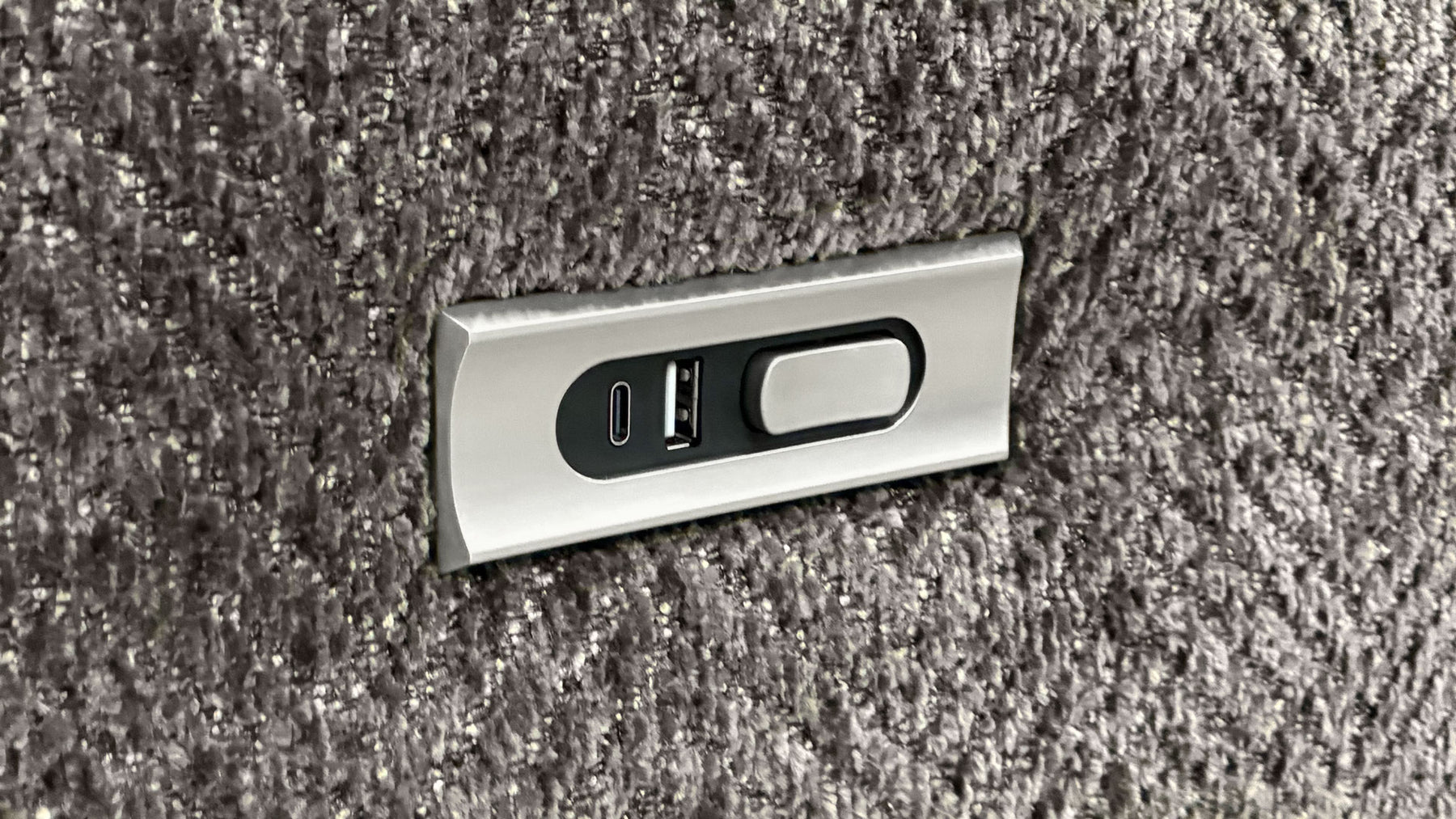 Metallic USB and power outlet panel on a textured gray surface