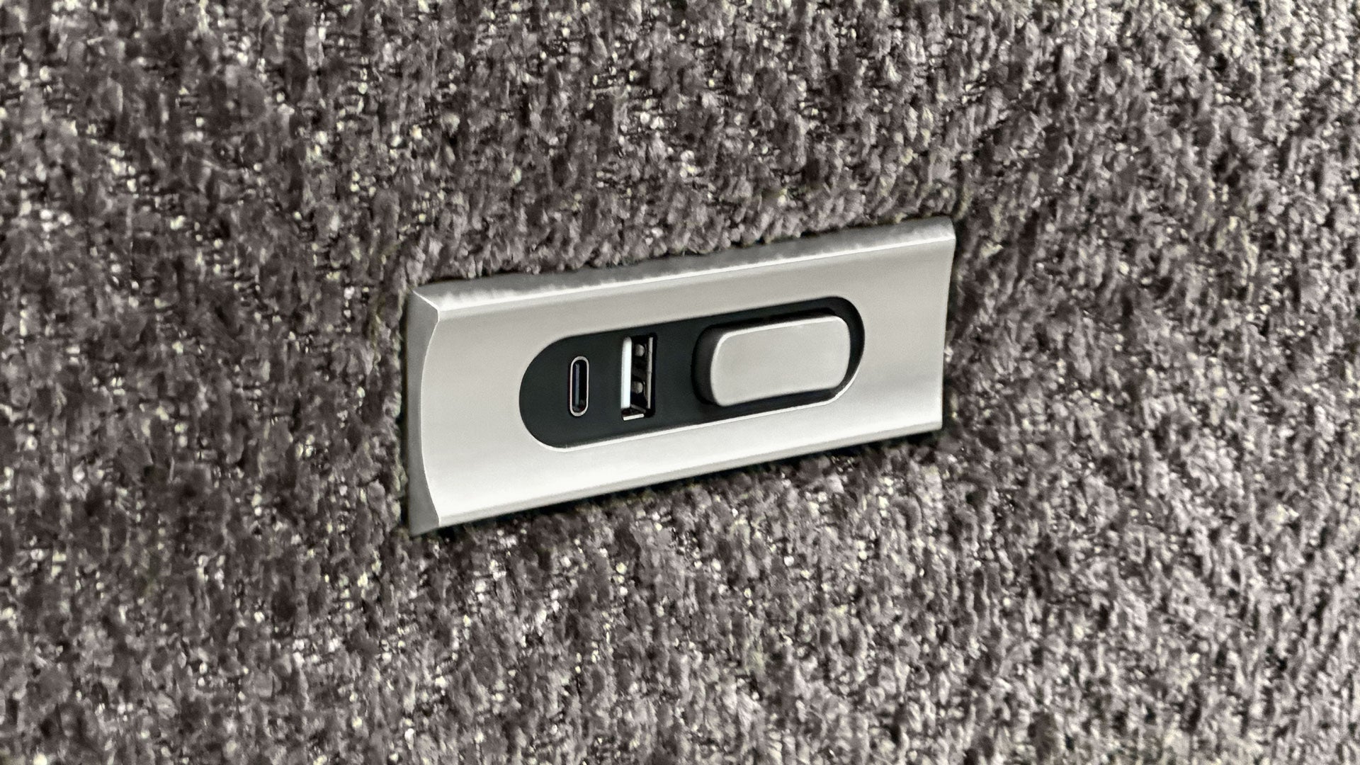 Metallic USB and power outlet panel on a textured gray surface