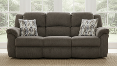 Gray sofa with patterned cushions in a room with large windows.