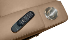Close-up of a beige leather massage chair armrest featuring a black remote control and a circular metallic control button, isolated on a white background.