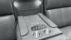 Close-up of a gray leather luxury vehicle interior center console with two cup holders, a control panel, and armrests.