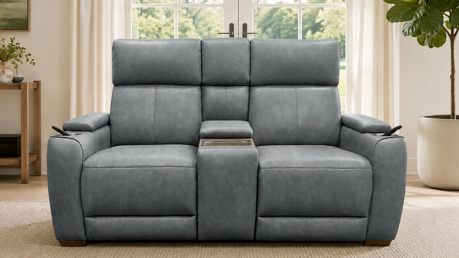A gray reclining loveseat sofa with a center console and cup holders, shown in a bright living room setting.