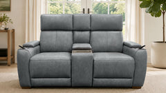 A gray reclining loveseat sofa with a center console and cup holders, shown in a bright living room setting.