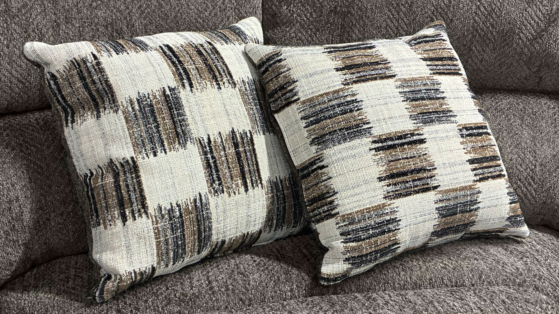 Two patterned pillows on a gray sofa