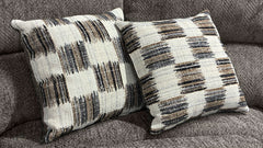 Two patterned pillows on a gray sofa