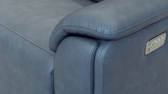 Close-up of a blue leather sofa with a metallic logo plate.