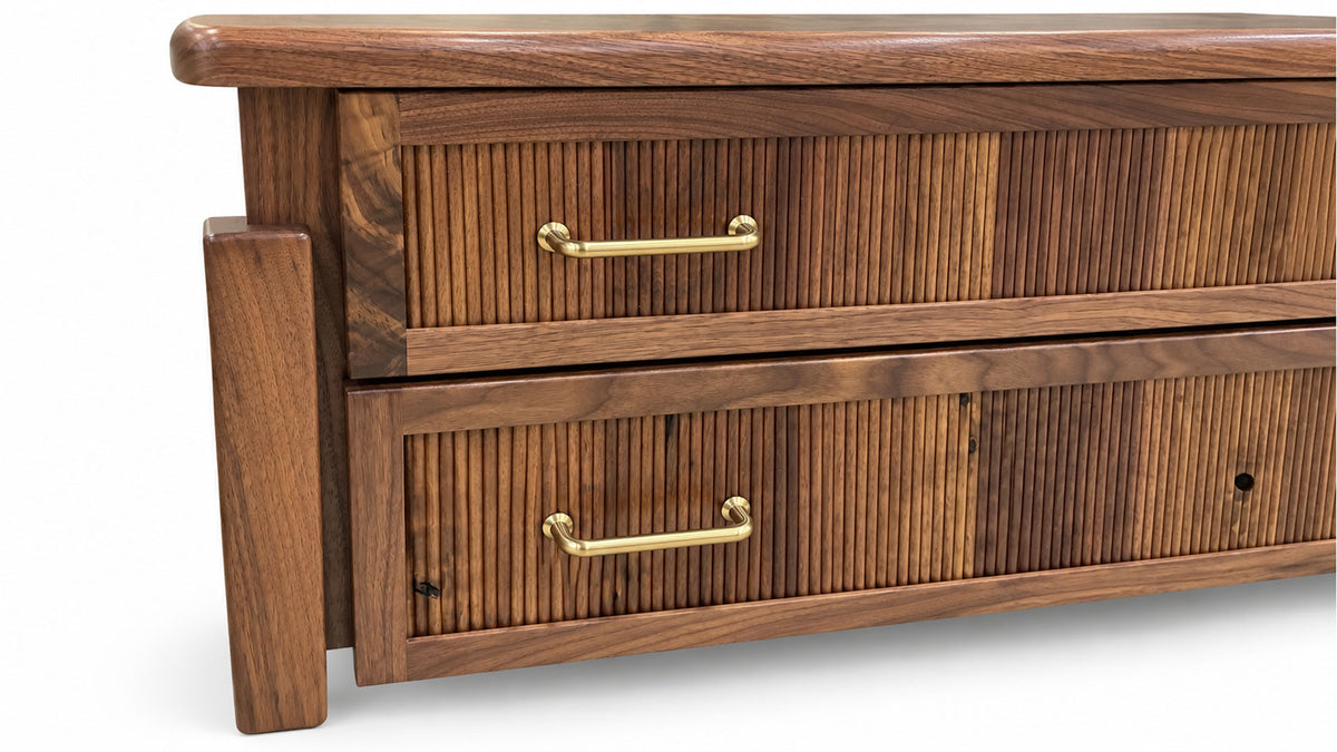 A close-up of a wooden dresser with two drawers featuring vertical slat fronts and brass bar handles, shown against a plain white background.