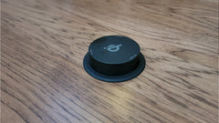 Black circular device with a logo on a wooden surface