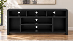A modern black wooden media console with multiple open shelves and three circular white light accents, set against a warm beige wall with a framed print and a plant visible on the left.