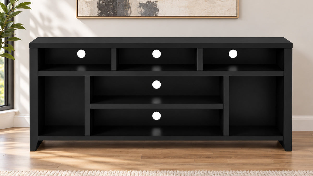 A modern black wooden media console with multiple open shelves and three circular white light accents, set against a warm beige wall with a framed print and a plant visible on the left.