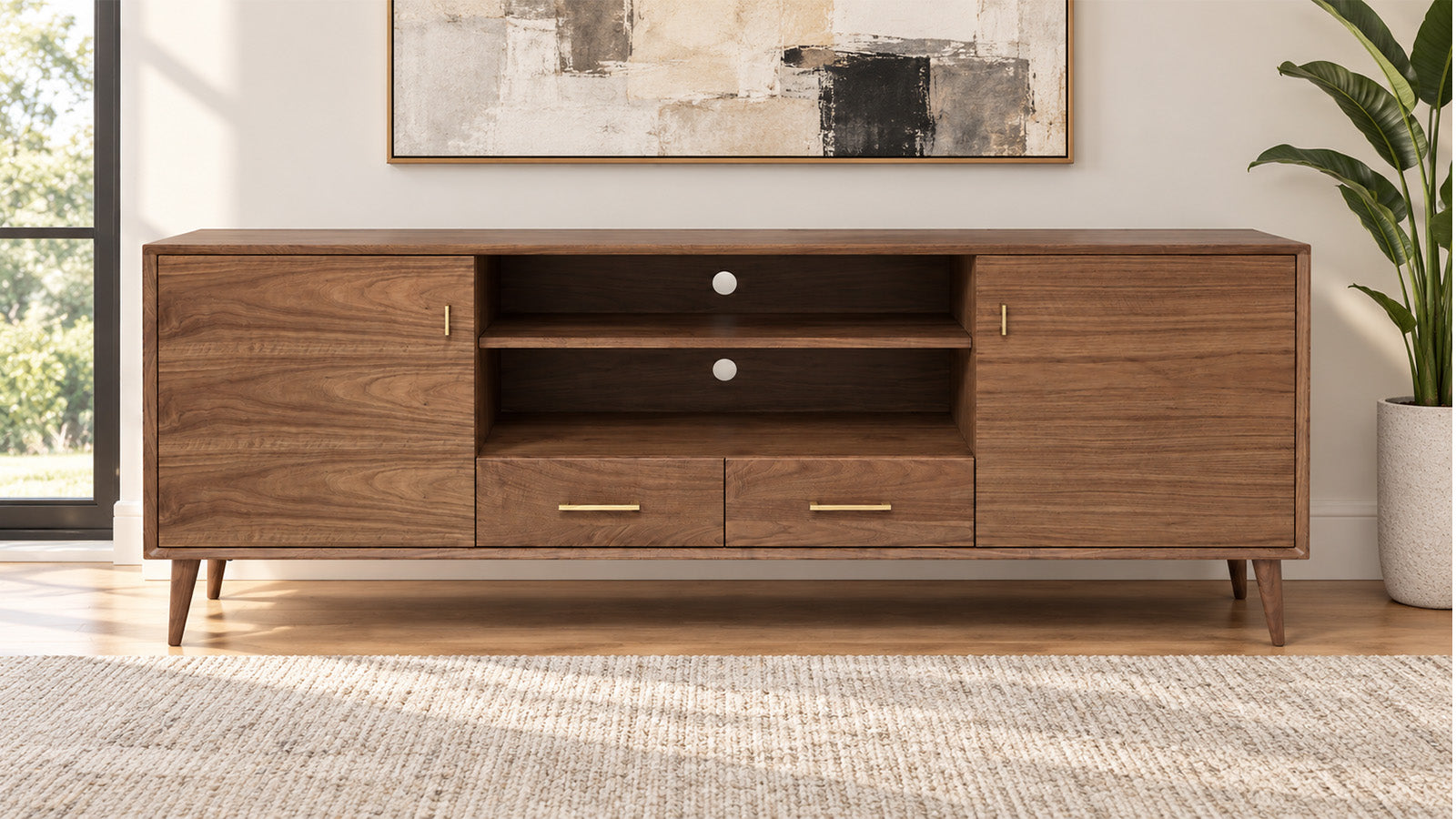 A mid-century modern wooden TV stand or media console with a warm brown wood finish, featuring two cabinet doors, two drawers, and open shelving, shown in a styled living room setting.