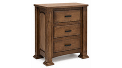 A three-drawer wooden nightstand with a medium brown finish, featuring dark metal drawer pulls and decorative block feet, shown on a white background.
