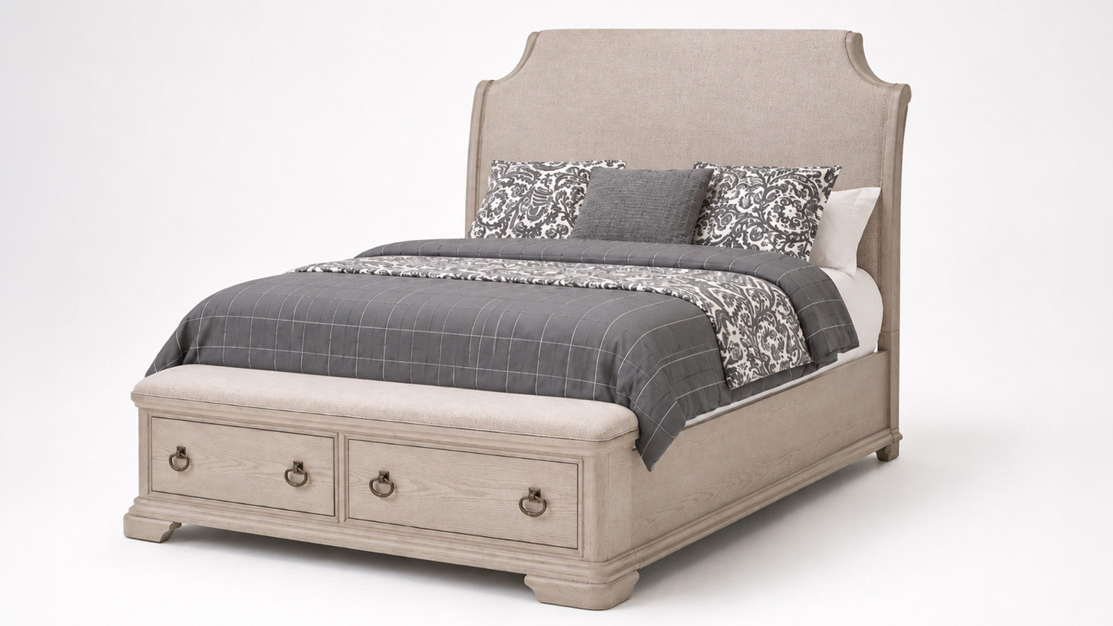 A light beige upholstered bed with a tall curved headboard and built-in storage drawers at the foot, styled with gray and black patterned bedding on a white studio background.