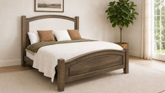 Wooden bed with white bedding in a room with a plant and window.