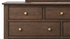 Cómoda de madera con cuatro cajones y pomos de latón sobre fondo blanco