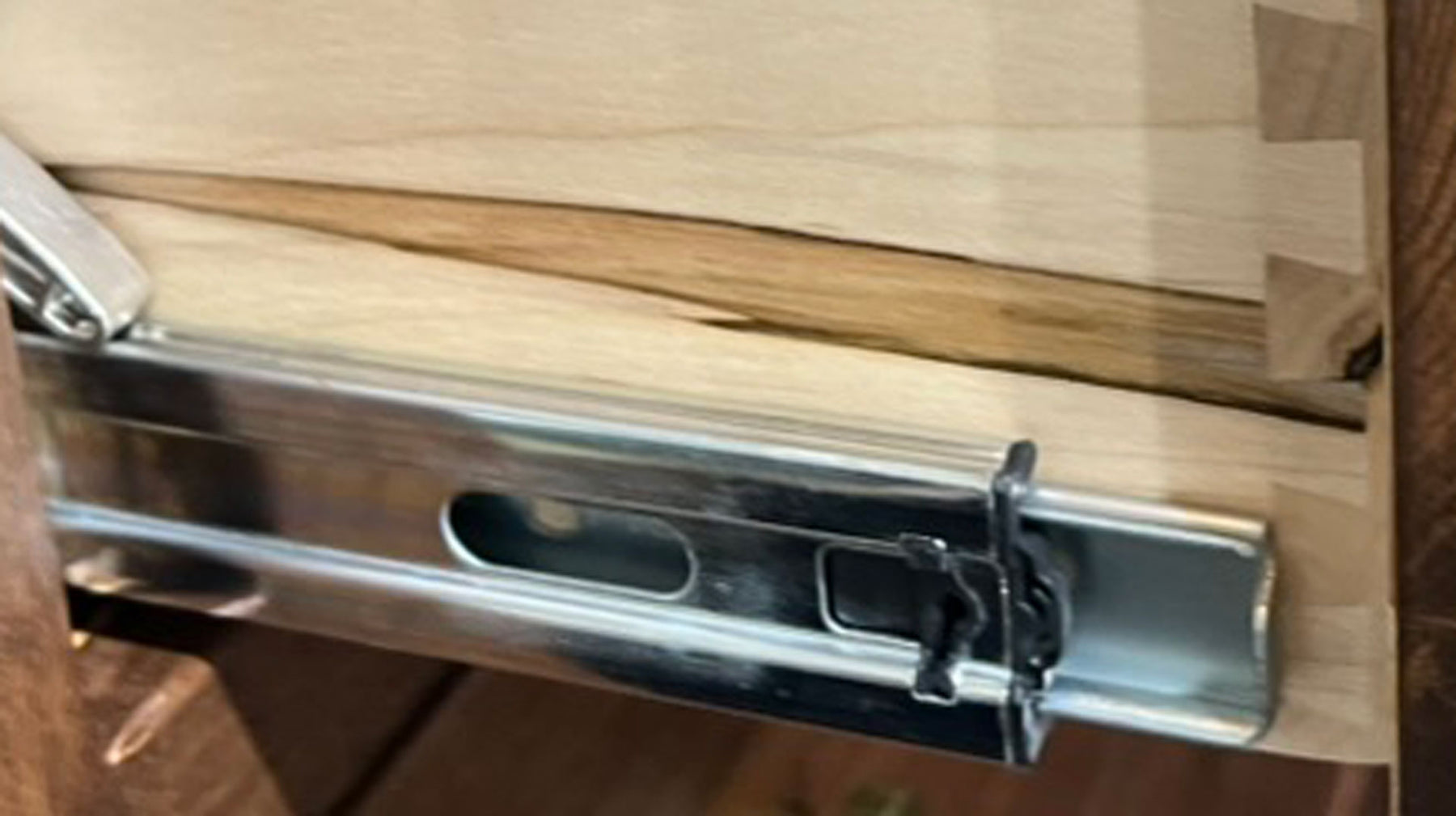 Guía metálica para cajones sobre una superficie de madera